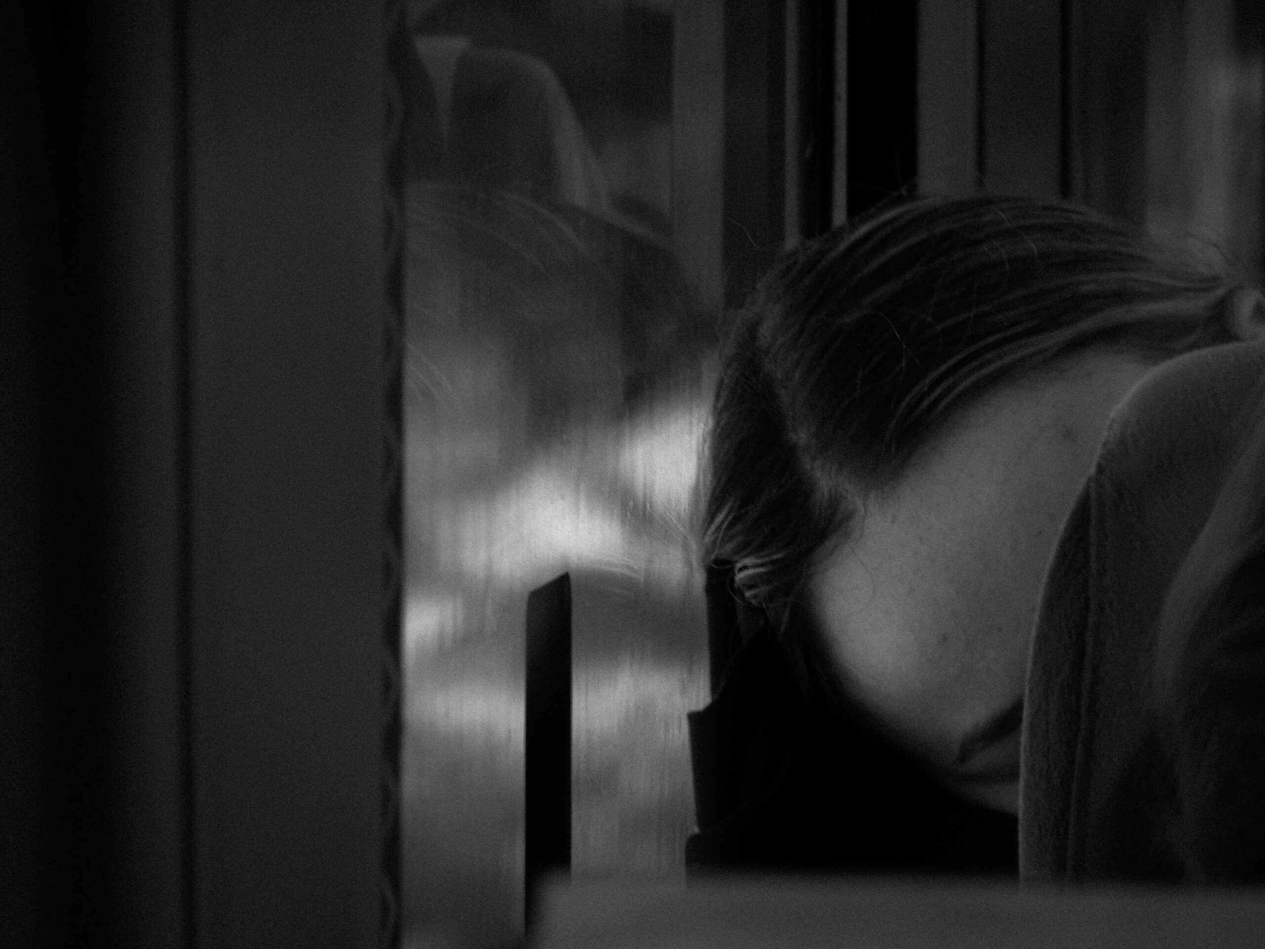 Donna con la testa appoggiata al finestrino di un treno in una foto in bianco e nero che esprime tristezza, dolore e senso di colpa per il lutto e l'eutanasia del proprio cane malato.